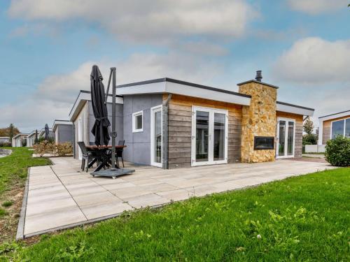 a small house with a patio and an outdoor fireplace at Holiday Home Green Resort Mooi Bemelen-1 by Interhome in Bemelen