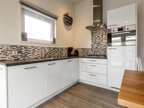 a white kitchen with white cabinets and a window at Holiday Home Green Resort Mooi Bemelen-1 by Interhome in Bemelen