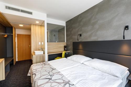a bedroom with a large white bed and a bathroom at Harmony Club Hotel in Ostrava