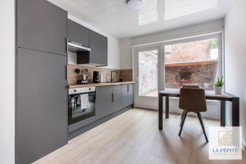 a kitchen with a dining table and a window at Residence Poterne in Valenciennes