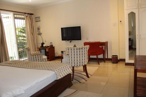a bedroom with a bed and chairs and a television at Sovereign Hotel in Kisumu