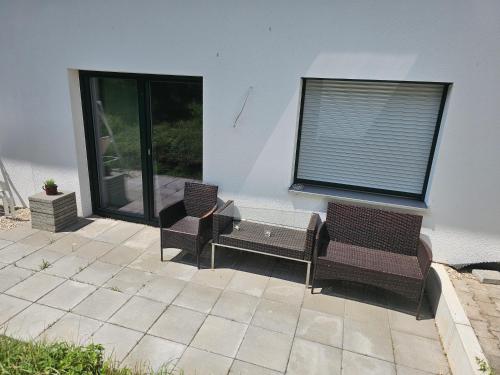 a patio with three chairs and a window at Moderne Ferienwohnung auf Rups Hof in Oberhöcking