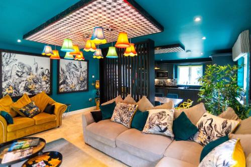 a living room with yellow couches and blue walls at Trewhiddle Retreat V3 by Together Travel - Luxury 4-Bedroom Villa in St Austell