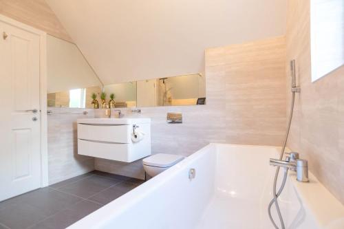 a bathroom with a tub and a toilet and a sink at Trewhiddle Retreat V3 by Together Travel - Luxury 4-Bedroom Villa in St Austell