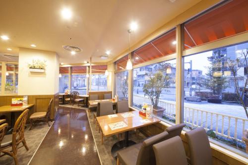 un restaurante con mesas, sillas y ventanas grandes en Richmond Hotel Matsumoto, en Matsumoto