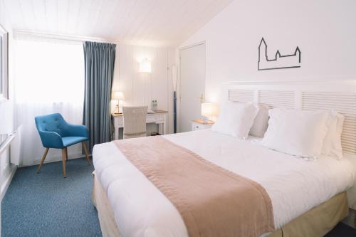 ein Schlafzimmer mit einem großen weißen Bett und einem blauen Stuhl in der Unterkunft Fleur de Sel in Noirmoutier-en-l'lle