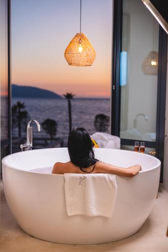 a woman sitting in a bath tub with a view of the ocean at Azar Luxury Suites in Vlorë