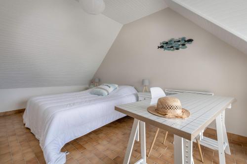 a bedroom with a bed and a table with a hat at Détente au calme et près de la plage in Saint-Gildas-de-Rhuys