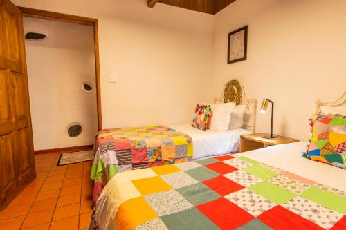 a bedroom with two beds with colorful quilts at Aldeia da Cuada in Faja Grande