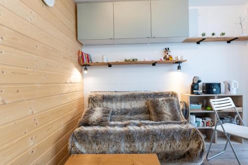 eine Couch in einem Raum mit Holzwänden in der Unterkunft SweetLoc - Appt au pied des Pistes au Corbier in Villarembert