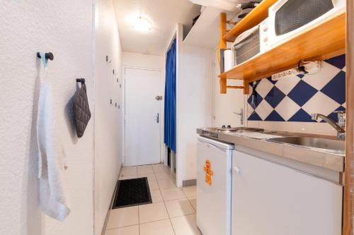 eine kleine Küche mit weißen Schränken und einer Spüle in der Unterkunft SweetLoc - Appt au pied des Pistes au Corbier in Villarembert