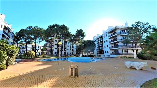 アルブフェイラにあるApartamentos Pinheiro Sol na Praia da Falésiaの白いベンチ2つと建物のある広い中庭