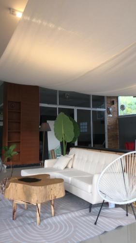 TIL DAWN Phuket في Ka Rorn: غرفة معيشة مع أريكة بيضاء وطاولة قهوة
