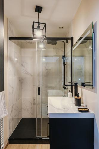 une salle de bain avec une douche avec un lavabo et un miroir dans l'établissement Appartement 2 pièces L'industriel en centre-ville de Cambrai, à Cambrai