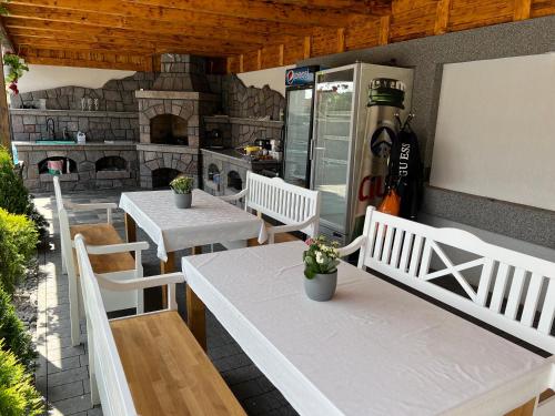 un patio con mesas y sillas blancas y una chimenea en Guesthouse Viktoria Pensiune, en Praid