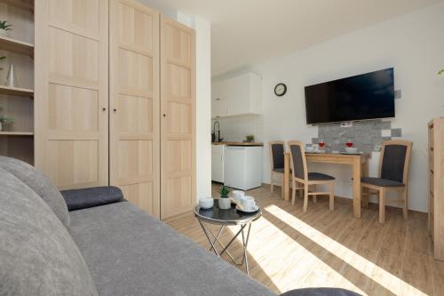 a living room with a couch and a table and a kitchen at Klimaty Bałtyku Studio with Terrace & Parking in Dziwnów by Renters in Dziwnów