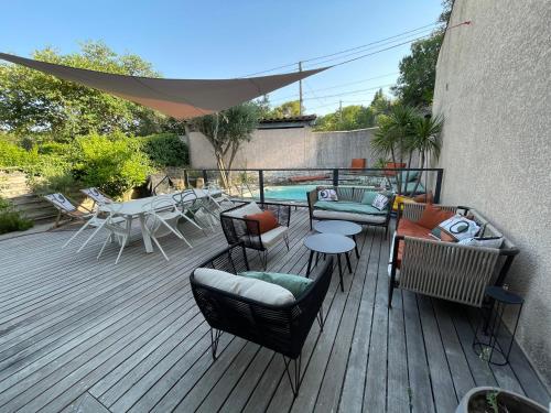 una terraza de madera con sillas y mesas y una piscina en Jolie villa à quelques pas du centre-ville. en Nimes