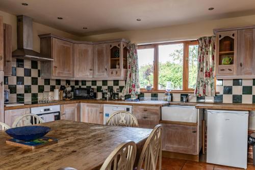 a kitchen with wooden cabinets and a wooden table at Cart Lodge - Holly Tree Barns in Halesworth