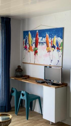 a desk with a television and a painting on the wall at T3 - TERRASSE 30 m2 VUE OCEAN, 2 CHAMBRES, parking privatif et piscine en été in Lacanau-Océan