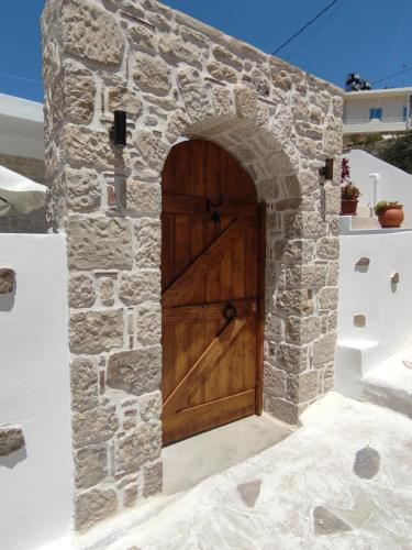 une grande porte en bois dans un mur en pierre dans l'établissement La maison d Aspasia, à Kamilárion