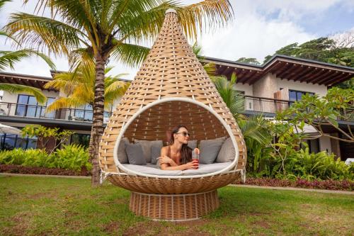 a woman sitting in a hammock in a wicker bed at Mango House Seychelles, LXR Hotels & Resorts in Baie Lazare Mahé
