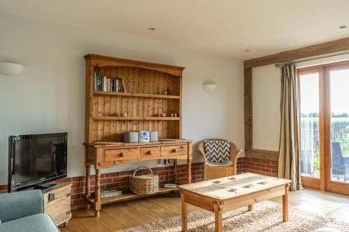 a living room with a tv and a table at The Dairy - Holly Tree Barns in Halesworth
