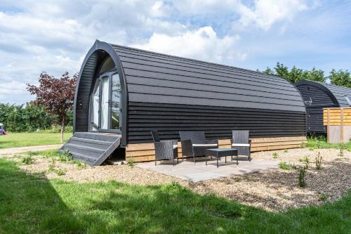 a small black building with a table and chairs at Glamping Pod Two - Holly Tree Barns in Halesworth
