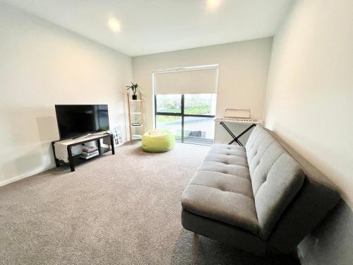 a living room with a couch and a television at A&J Queen bedroom-Quiet and brand new with reserve view in Auckland