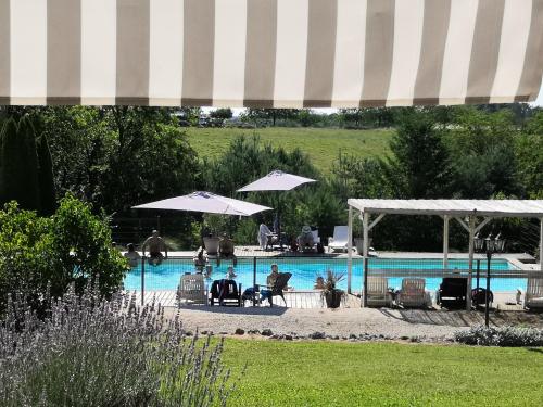 una piscina con sillas y sombrillas y gente sentada junto a ella en CAMPING HERMITAGE DES 4 SAISONS, en Saint-Julien-de-Bourdeilles