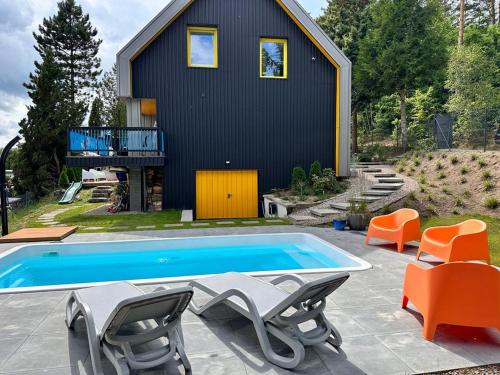 Kłaczno的住宿－HonoLulu Dom Wakacyjny z balią, sauną i basenem，一座带游泳池和一些椅子的房子