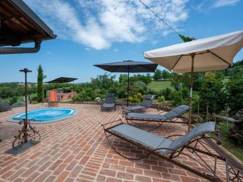 patio z 2 krzesłami, parasolem i basenem w obiekcie Holiday Home La Bell'aria by Interhome w mieście Tonco