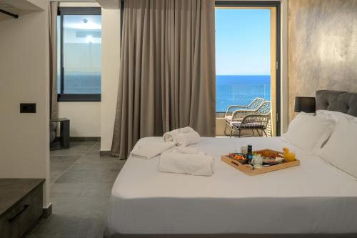 a bedroom with a white bed with a view of the ocean at Olive Green Studios and Apartments in Plomarion