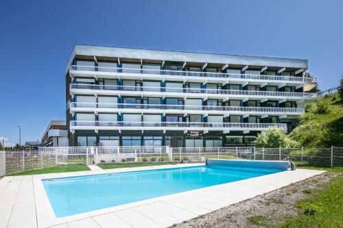 un immeuble avec piscine en face d'un immeuble dans l'établissement L'Ascension - Studio vue montagne, à Chamrousse