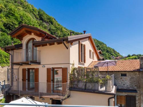 a house with a balcony and an umbrella at Apartment Casa degli Angeli by Interhome in Gravedona