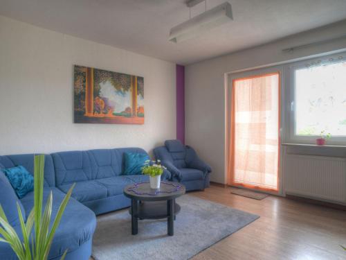 Apartment Alex by Interhome في Bromskirchen: غرفة معيشة مع أريكة زرقاء وطاولة