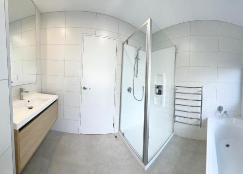 a white bathroom with a shower and a sink at A&J Queen bedroom-Quiet and brand new with reserve view in Auckland