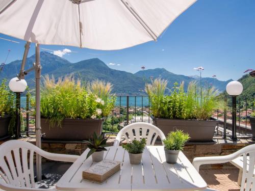 d'une table blanche avec des chaises et un parasol sur le balcon. dans l'établissement Holiday Home Villa Anna by Interhome, à Dongo