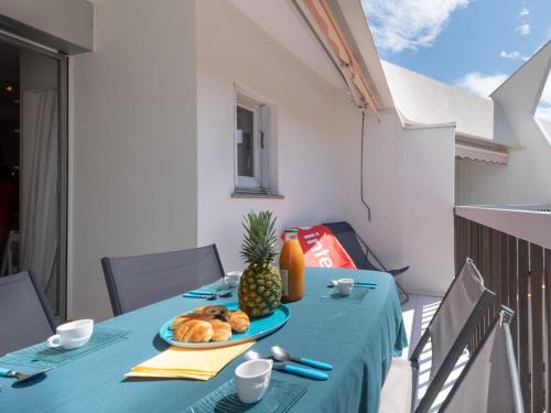 une table avec une assiette de pain et un ananas dessus dans l'établissement Apartment Les Flamants Roses-9 by Interhome, à La Grande Motte
