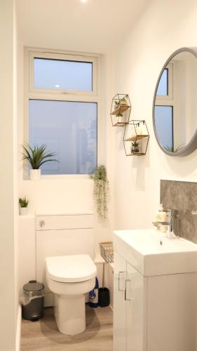 uma casa de banho com um WC branco e um espelho. em Modern Two Bedroom By Keysleeps Short Lets Northampton With Free Parking Garden Contractor Leisure 