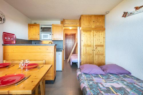 une petite cuisine avec un lit et une table en bois dans l'établissement Le Vernon - Studio vue montagne près des pistes, à Chamrousse