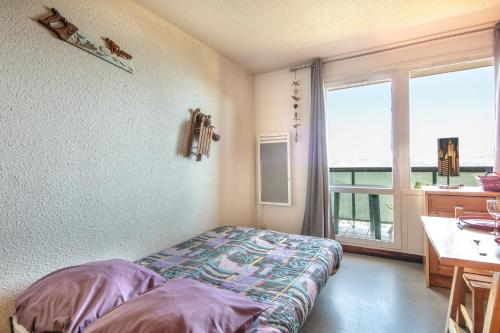 a room with a bed and a desk and a window at Le Vernon - Studio vue montagne près des pistes in Chamrousse