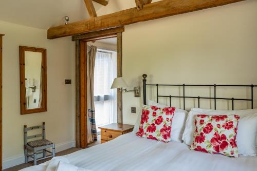a bedroom with a bed with red and white pillows at The Stables - Holly Tree Barns in Halesworth