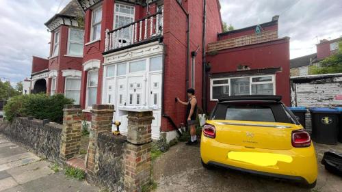 a yellow car parked in front of a house at Lovely flat near train station and central london in London