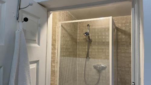 a shower with a shower head in a bathroom at Lovely flat near train station and central london in London