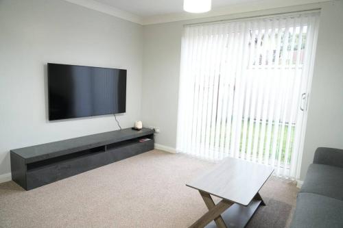 a living room with a flat screen tv on a wall at Harmony in Bicester in Bicester