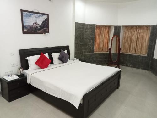 a bedroom with a large bed with red pillows at Aestus Adventure and Wellness Centre in Kasauli