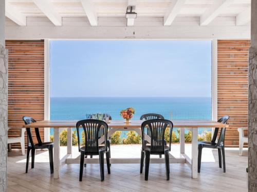 a dining room with a table and chairs and the ocean at Villa Orizzonte Holidays by Interhome in Realmonte