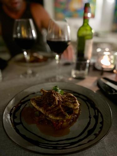 a plate of food on a table with two glasses of wine at Cosy Guest House Sous le Badamier in Grand Baie