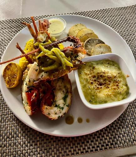 a plate of food with seafood and a bowl of sauce at Cosy Guest House Sous le Badamier in Grand Baie