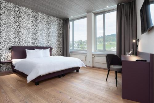 a bedroom with a bed and a desk and windows at b-smart hotel Menziken in Menziken